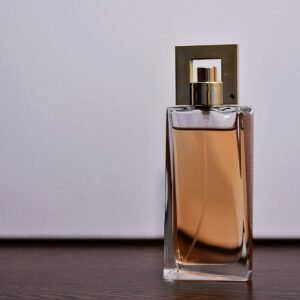 Stylish close-up of a transparent glass perfume bottle on a wooden surface.